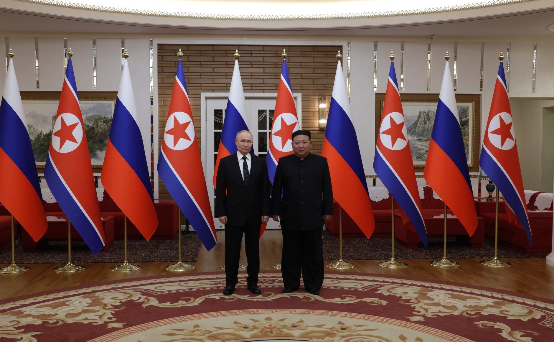Kim Jong Un standing with Vladimir Putin in front of North Korean and Russian flags in Pyongyang