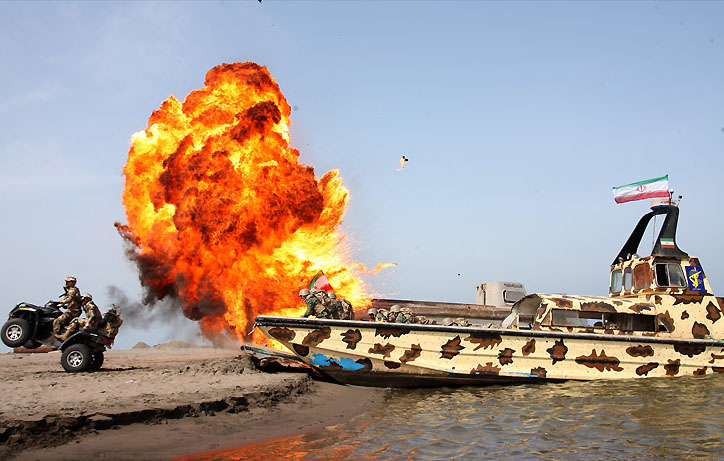 A camouflaged IRGC naval boat flying the Iranian flag during a naval exercise, Iran Hormuz shipping tactics